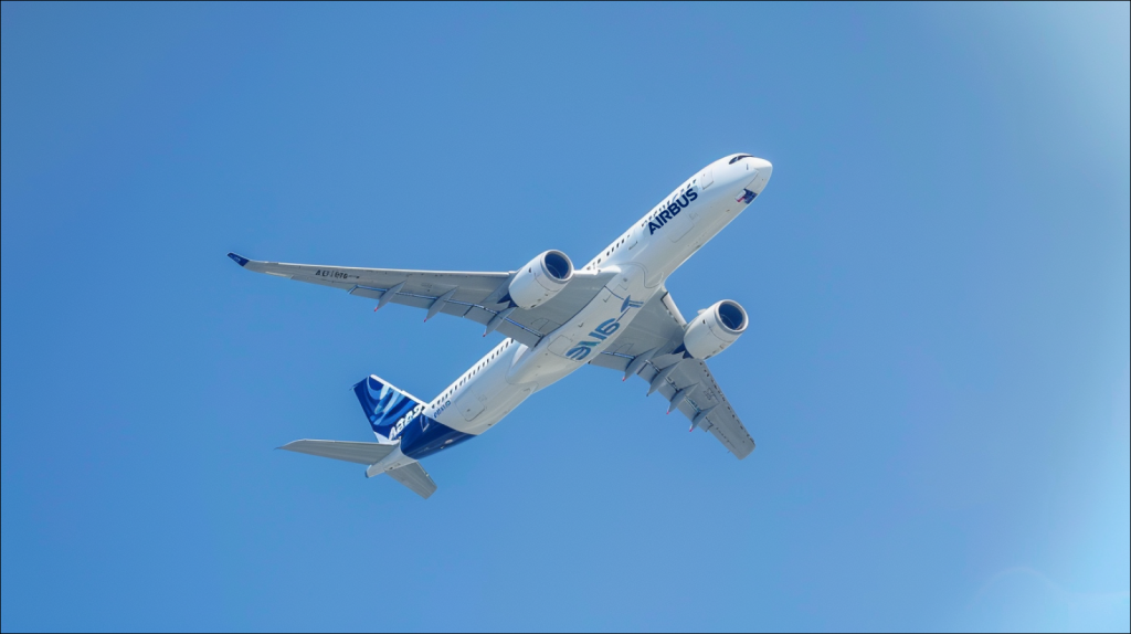 Ein Airbus-Flugzeug ist mitten im Flug vor einem klaren blauen Himmel.