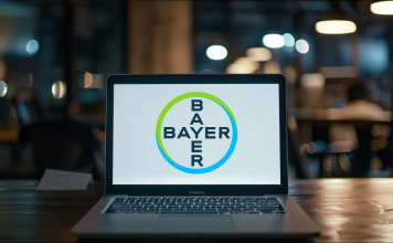 Ein Laptop steht auf einem Tisch, auf dem Bildschirm ist deutlich das Logo von Bayer zu sehen.