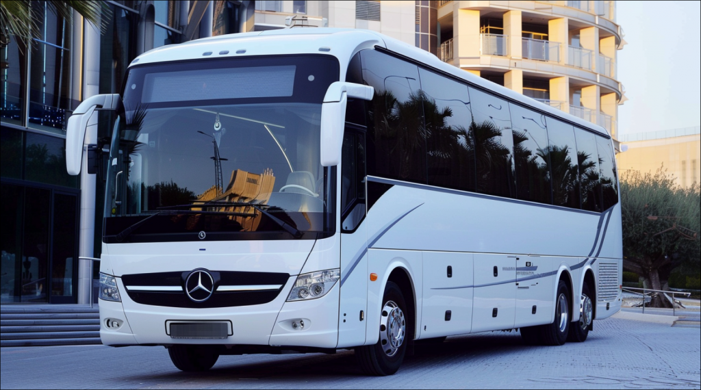 Ein moderner weißer Mercedes-Benz Reisebus vor einem urbanen Gebäudekomplex.