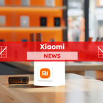 ein Werbedisplay mit einem Würfel mit dem Xiaomi-Logo in einem Ladenumfeld, mit elektronischen Geräten im Hintergrund, mit einem Xiaomi NEWS-Banner