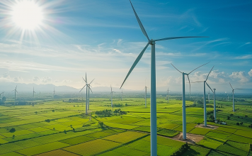 Luftaufnahme eines weitläufigen Windparks mit mehreren Nordex-Turbinen und grünen Feldern.