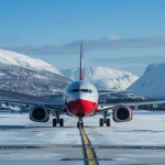 Norwegian Air Shuttle-Flugzeug rollt auf schneebedecktem Rollfeld mit Bergen im Hintergrund