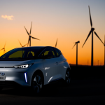 BYD-Elektrofahrzeug vor Windturbinen bei Sonnenuntergang